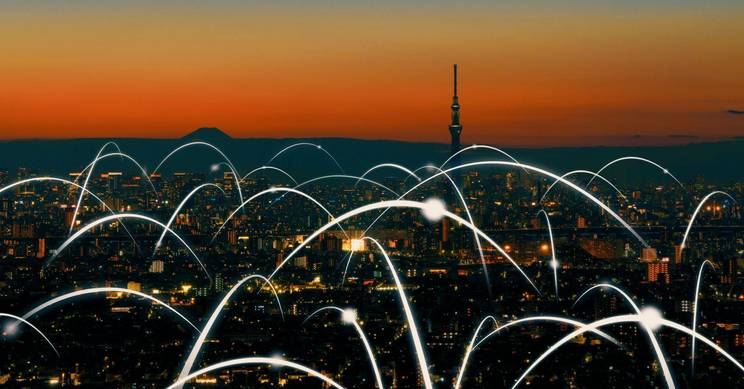 Vista panorámica de una ciudad al atardecer con conexiones digitales representadas en la imagen.