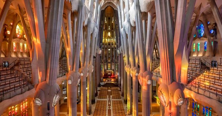 Vista interior de la Basílica de la Sagrada Familia, destacando sus columnas y vitrales coloreados.