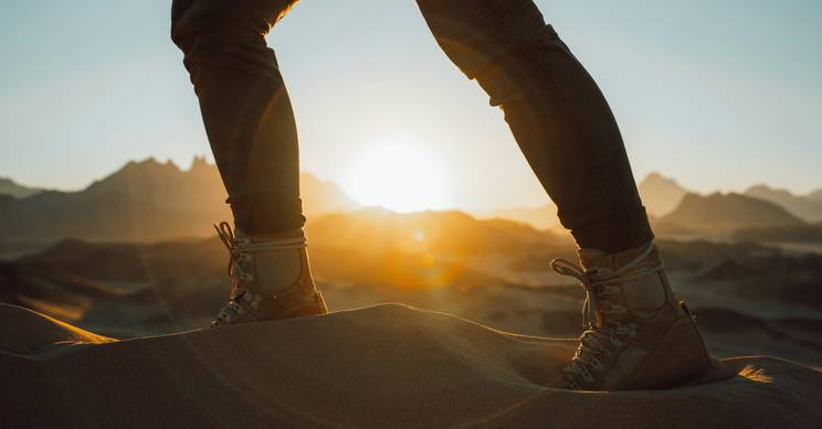 Persona de pie sobre las dunas al atardecer.