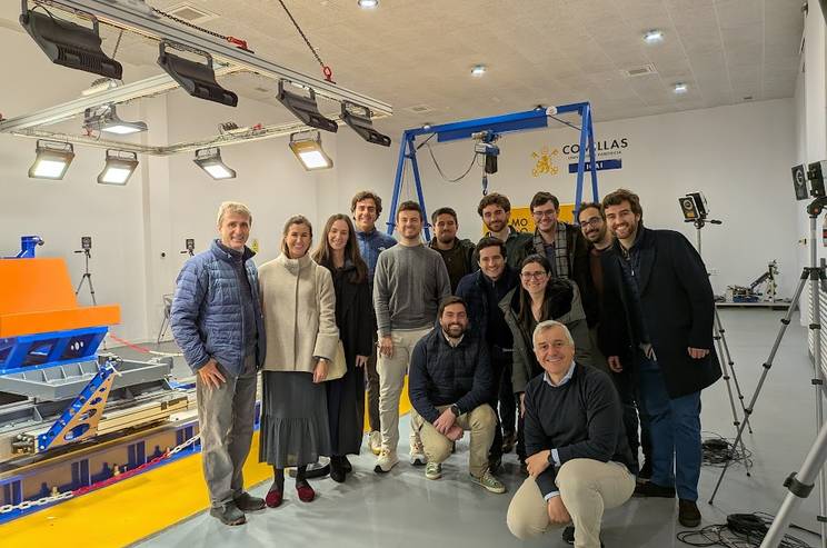 Un grupo de personas posando en un laboratorio con equipos tecnológicos.
