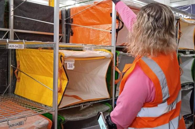 Una trabajadora con chaleco reflectante organiza cajas en un espacio de almacenamiento.