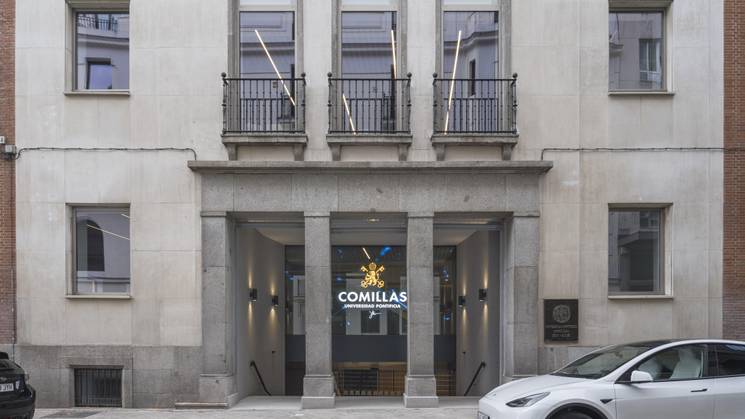 Edificio moderno con fachada de piedra y ventanas amplias ubicado en una calle tranquila.