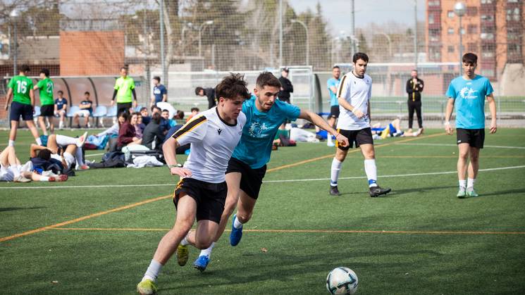 Dos jugadores de fútbol compiten por el balón en un campo de hierba.