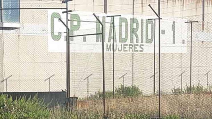 Vista exterior de un edificio grande y vallado con la inscripción 'C.P. MADRID-1 MUJERES' en una señalización al frente.