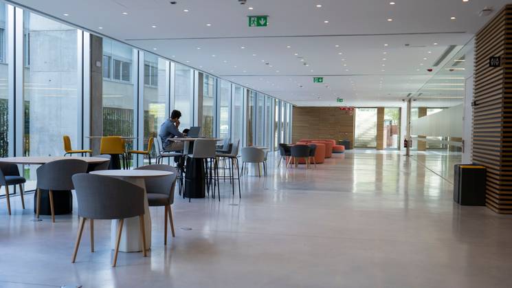 Un amplio espacio interior con mesas y sillas en un ambiente moderno y luminoso.