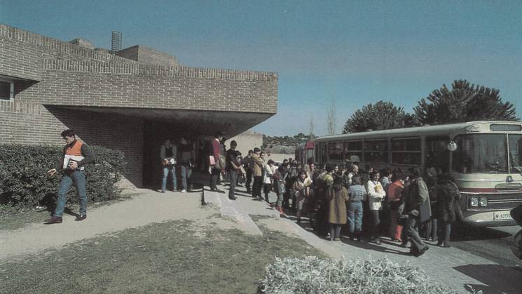 Group of people boarding a bus outside a modern building