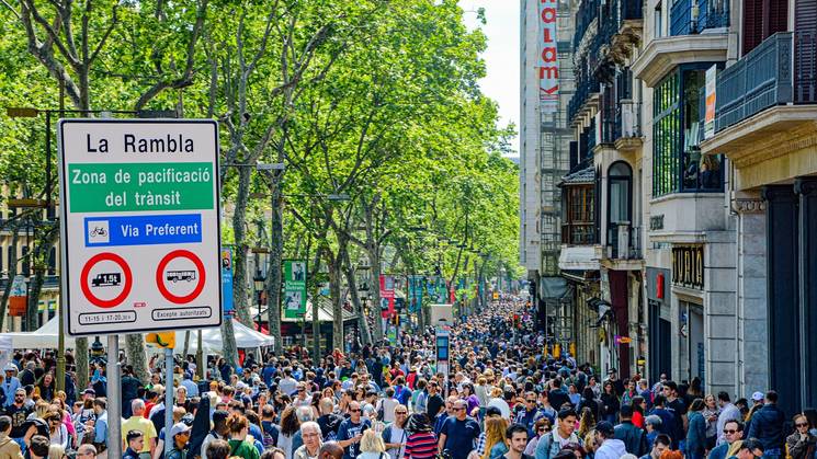 Una bulliciosa calle en La Rambla, llena de gente y rodeada de árboles y edificios.