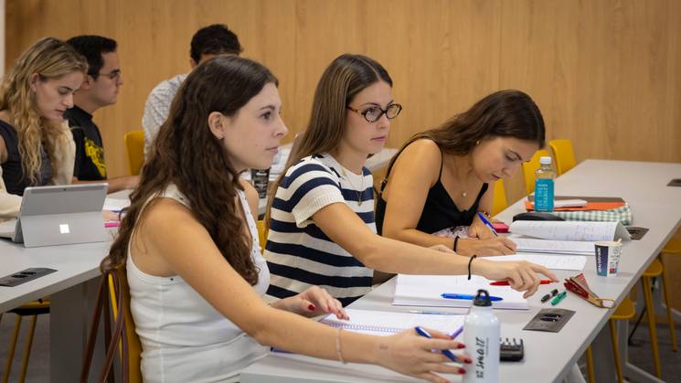 Un grupo de estudiantes concentrados en su trabajo en un aula moderna.