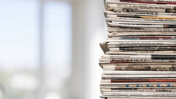 Una pila de periódicos apilados en un entorno luminoso.