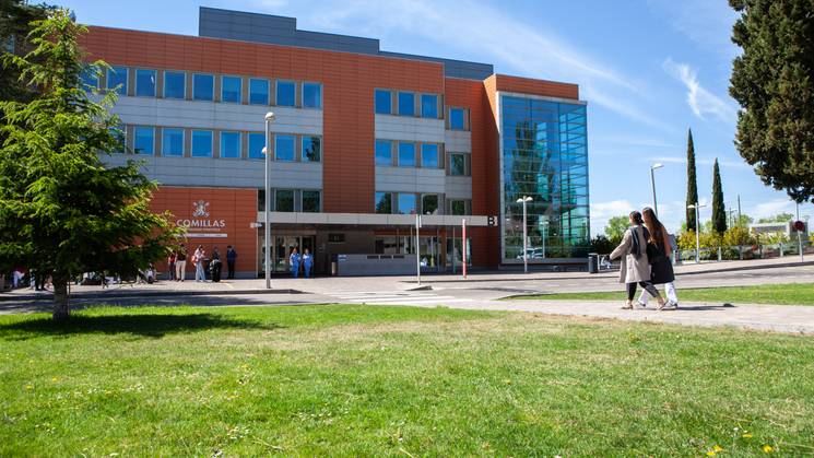 Edificio moderno situado en un campus con personas caminando por el área verde.