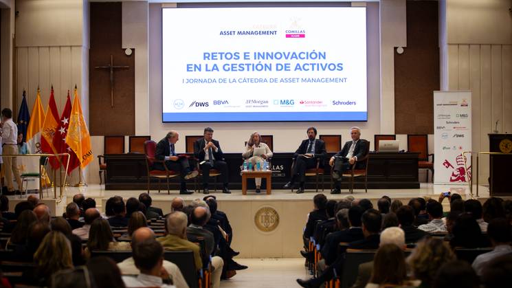 A conference panel discusses asset management innovation in a formal setting with an audience.