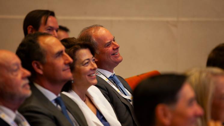 A group of adults in business attire sitting and smiling in an auditorium.