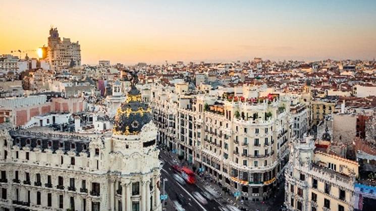 Una vista panorámica de la ciudad de Madrid al atardecer, con edificios emblemáticos y calles llenas de vida.
