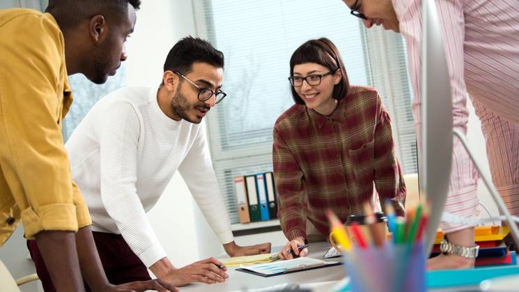 A diverse group of professionals collaboratively working around a table in an office setting.