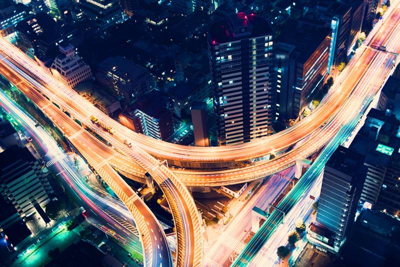 Una vista aérea de una intersección de carreteras iluminadas en una ciudad moderna durante la noche.