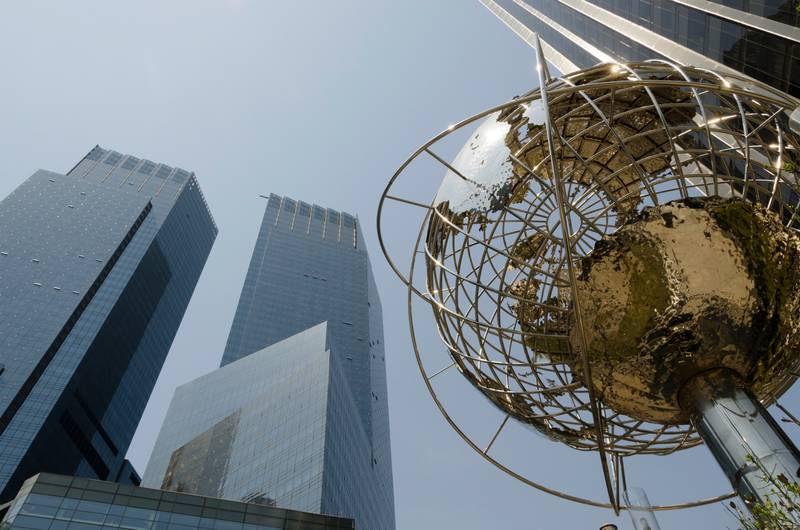 Una escultura del globo terráqueo en primer plano frente a altos edificios de cristal.