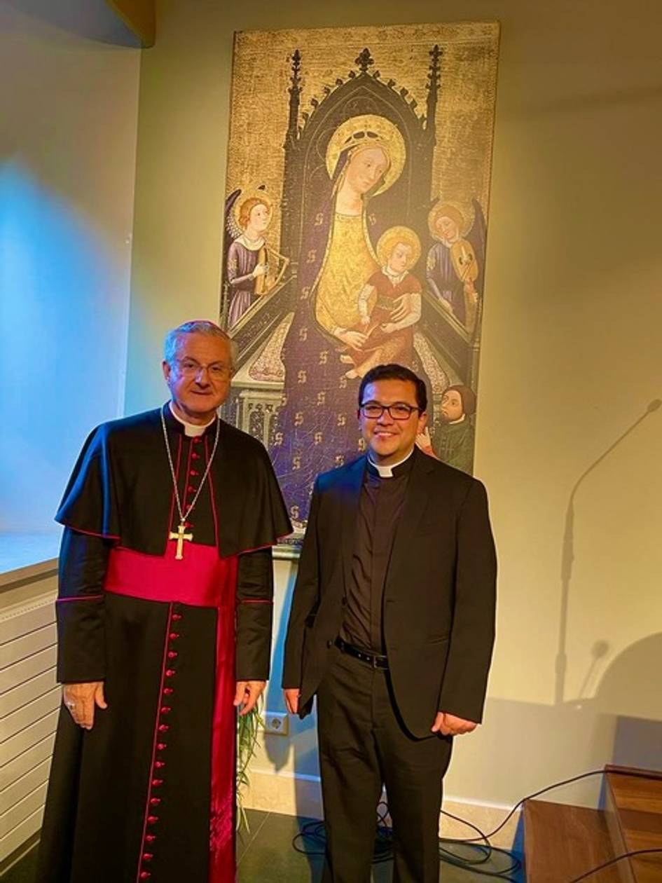 Dos clérigos sonriendo frente a un cuadro de la Virgen con el Niño.