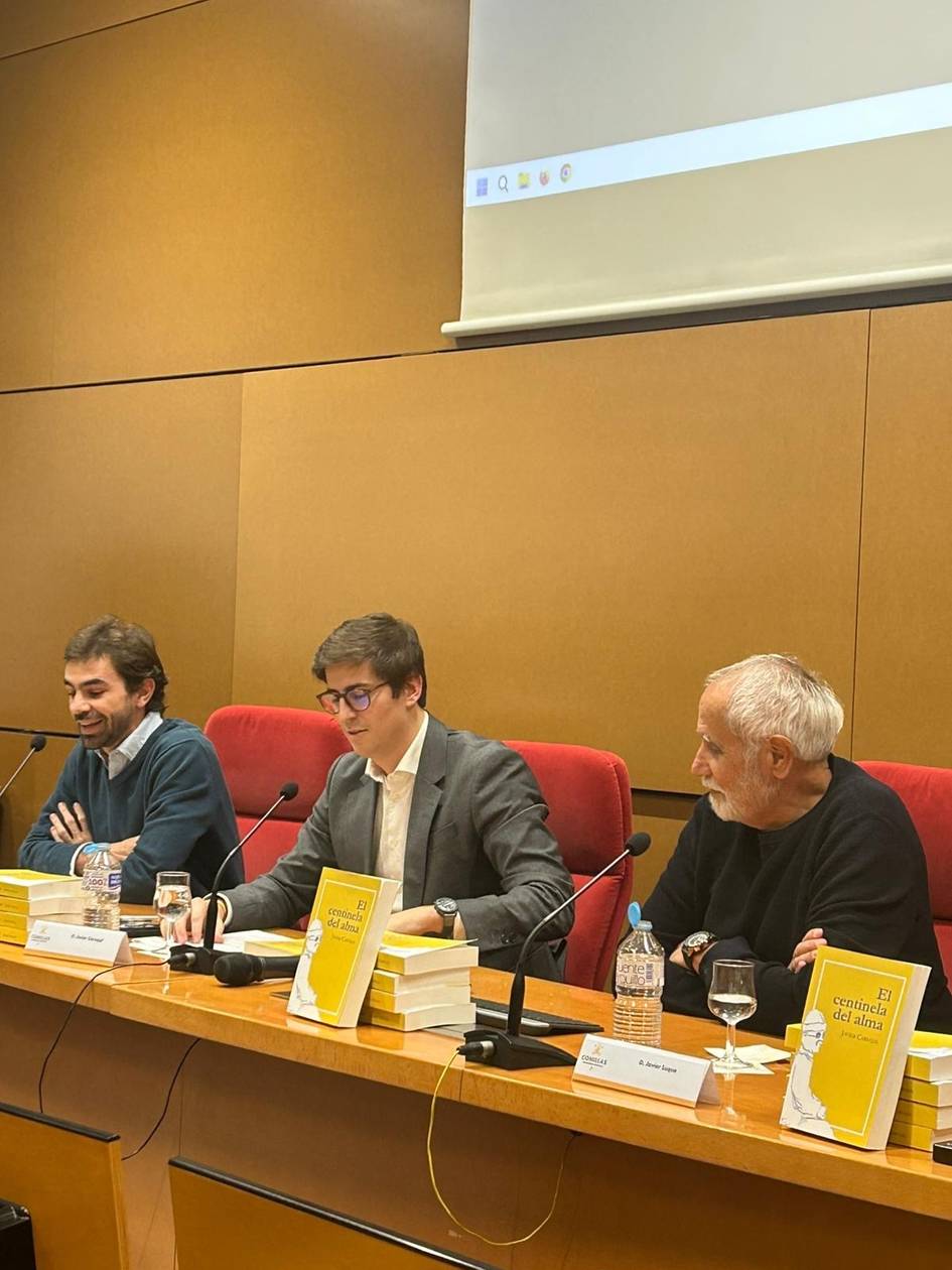 Tres hombres están sentados al frente de una mesa en un evento de presentación de libros.