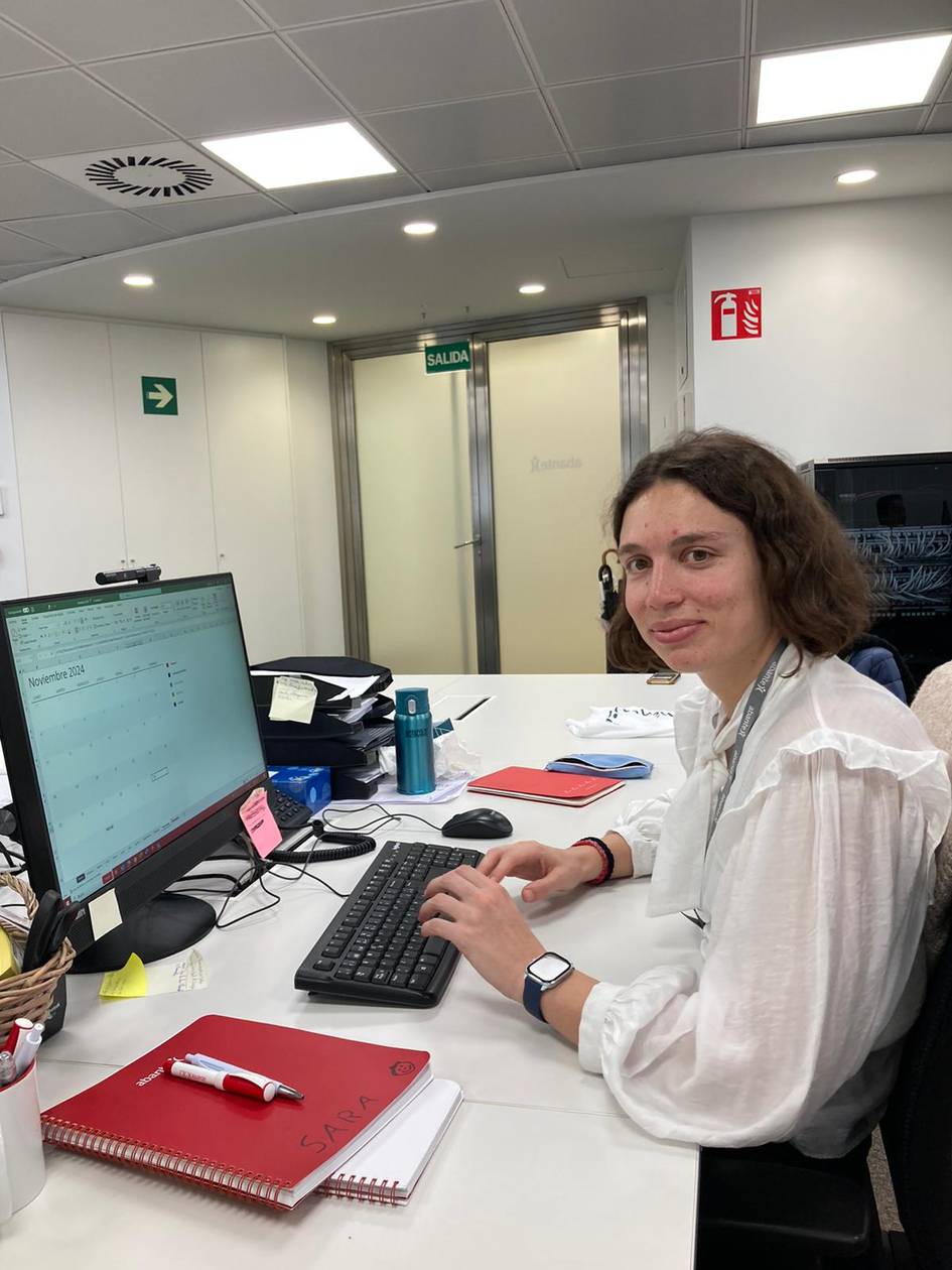 A woman sitting at a desk in an office working on a computer.