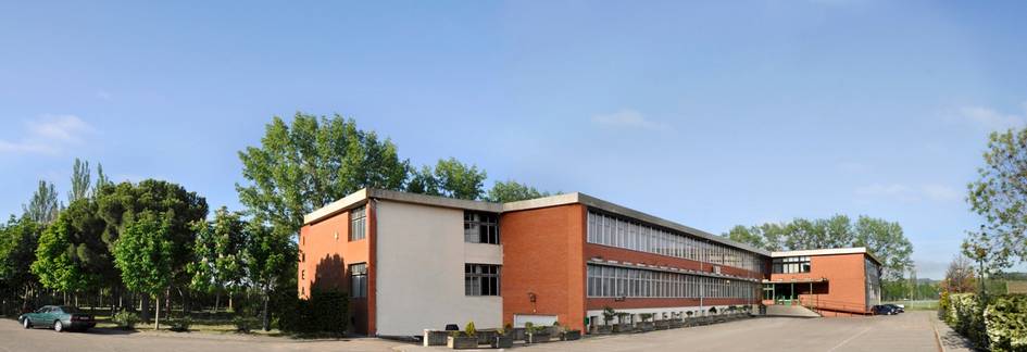 Panoramic view of a modern educational building with a spacious forecourt and surrounding greenery.