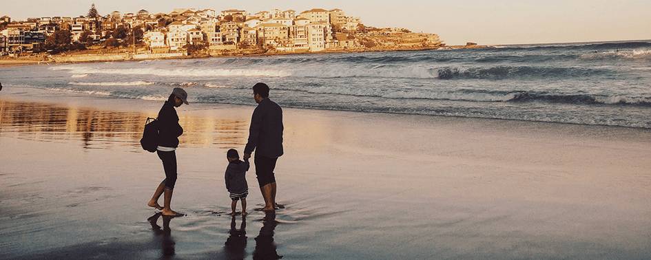 Una familia camina por la playa al atardecer.