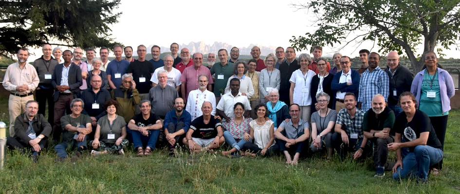 A large group of people posing for a photo outdoors with trees in the background.