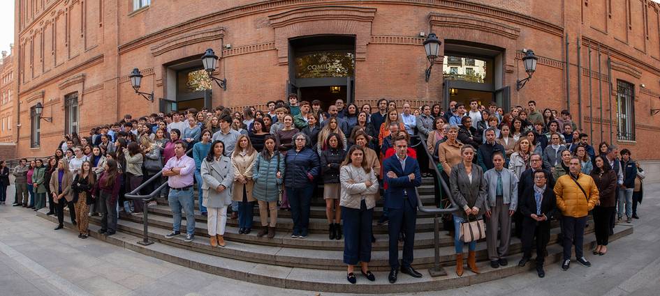 A large group of people gathered in front of a brick building with a wide staircase.