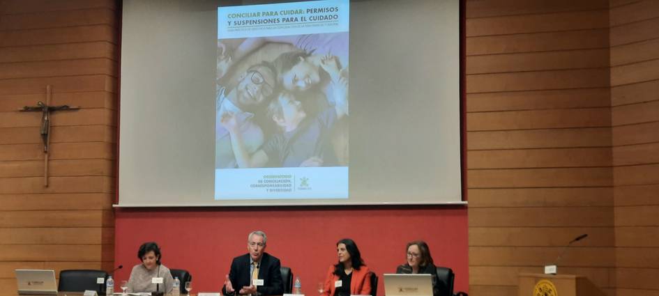 Un panel de discusión en un evento, con un cartel informativo al fondo y varios ponentes en la mesa.