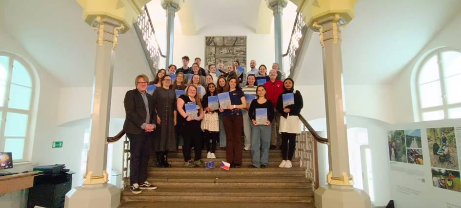 Un grupo diverso de personas posando en una escalera sostenido diplomas o certificados.