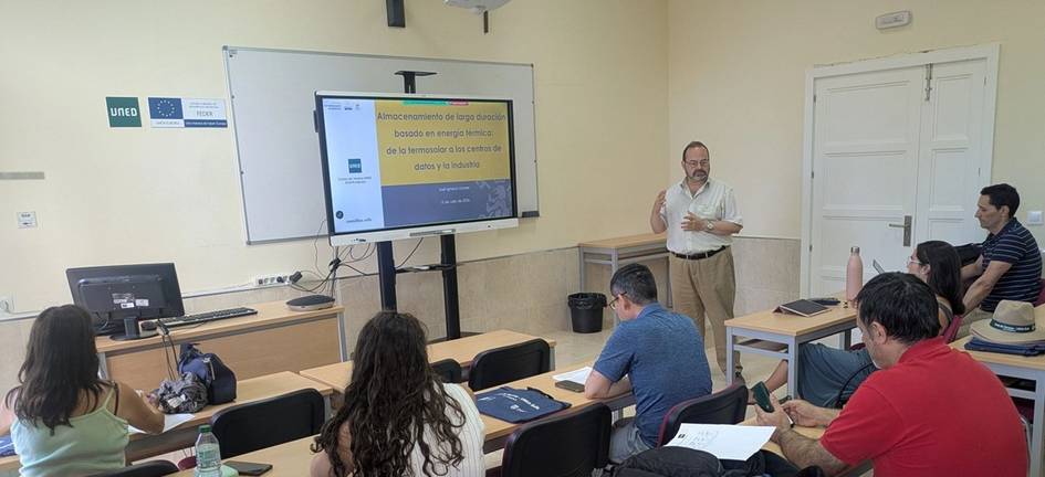 Un profesor está dando una clase en una sala con varios estudiantes atentos.