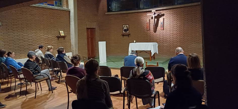 Una reunión de personas en un espacio con un altar y decoración sencilla.