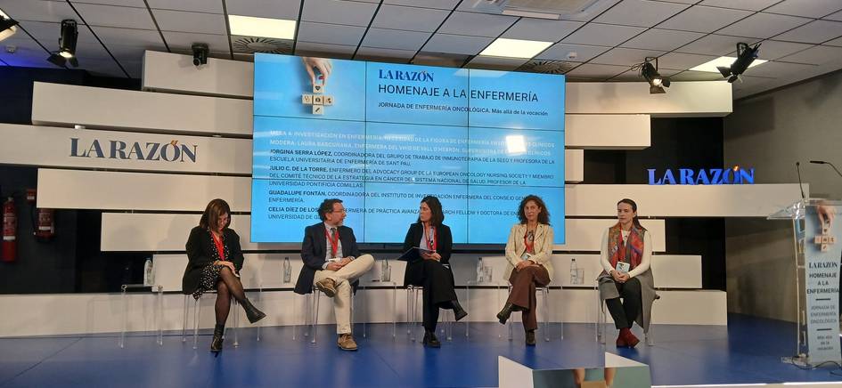 Un grupo de panelistas discuten en un evento de homenaje a la enfermería con una presentación en pantalla detrás de ellos.