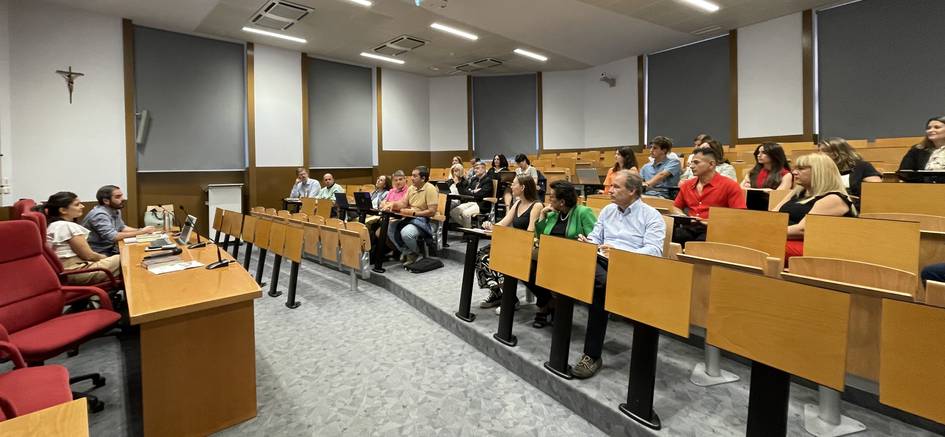 A group of people sitting in a lecture hall with a speaker at the front.