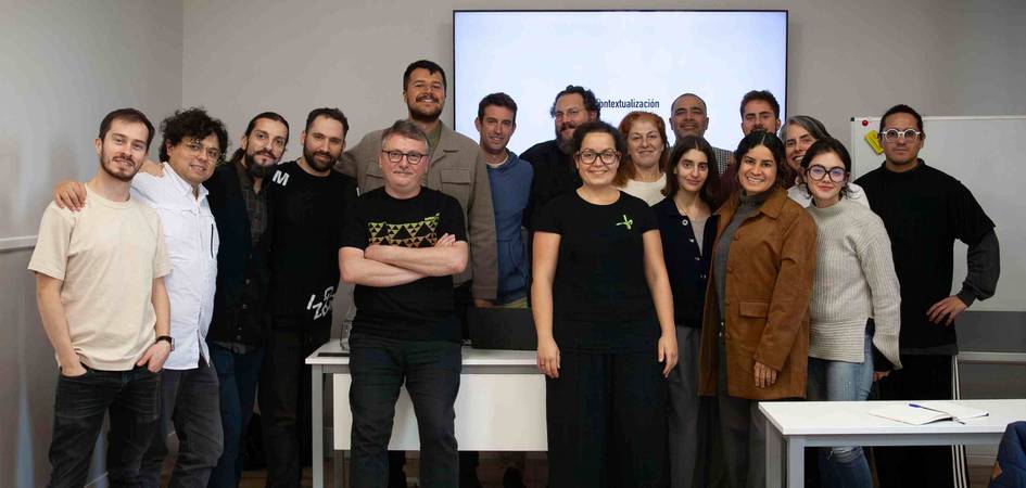 Grupo de personas sonriendo para una foto en un aula con pizarra blanca al fondo.