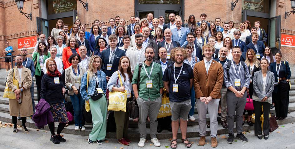 A large group of people posing together for a photo outside a building, wearing name tags and looking cheerful.