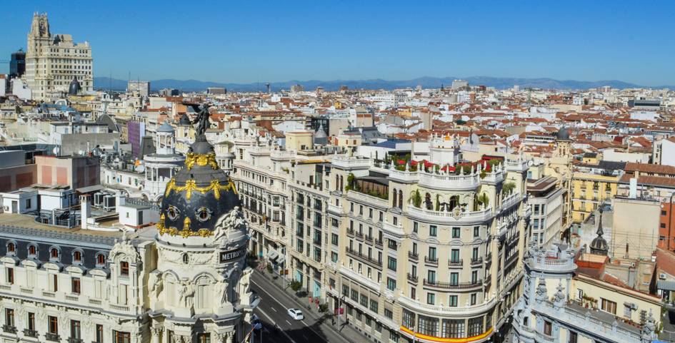 Aerial view of a bustling cityscape featuring historic European-style buildings under a clear blue sky.