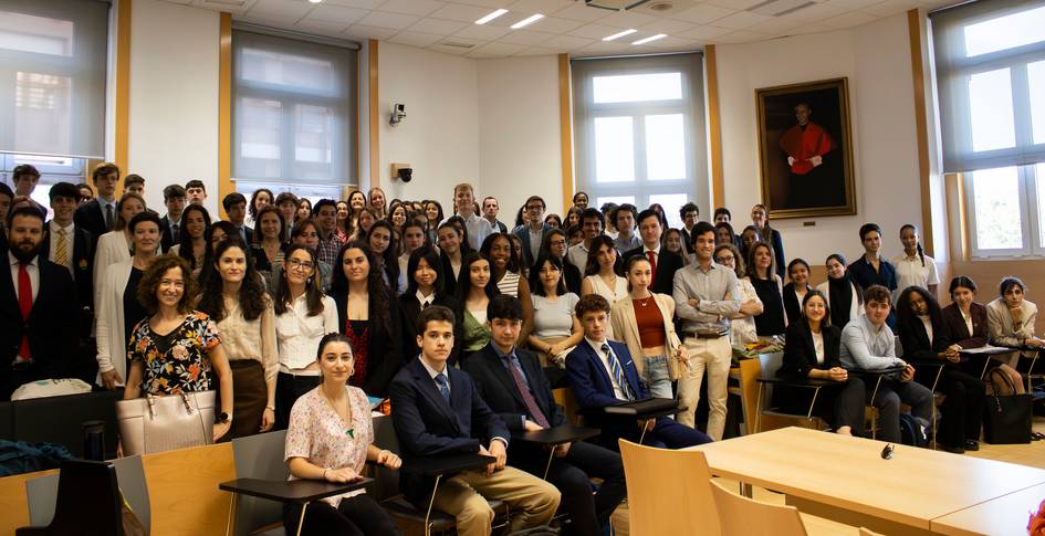 A group of people, mostly young adults, sitting and standing in a classroom setting.