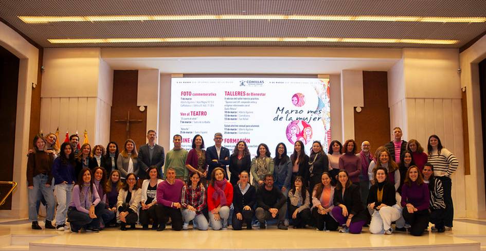 Un grupo grande de personas posando juntas en un evento relacionado con el mes de la mujer en un ambiente interior.