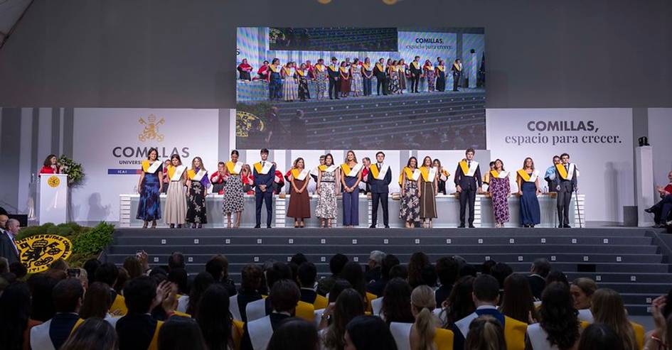 Ceremonia de graduación en la universidad con estudiantes en el escenario.