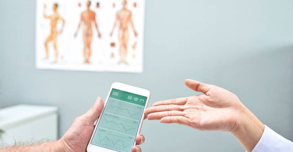 Una persona muestra un teléfono móvil con gráficos mientras otra persona extiende la mano en un entorno médico.