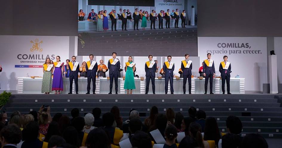 Ceremonia de graduación en la Universidad Comillas con estudiantes en el escenario.