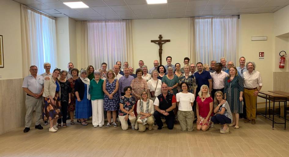 A large group of people posing for a photo in a room with a cross on the wall.