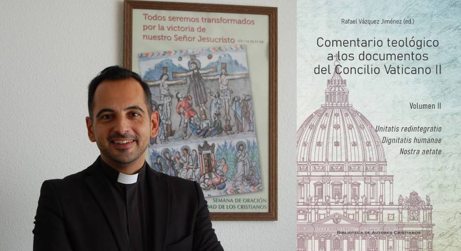 A man in a clerical collar stands in front of religious posters and a bookshelf with theological books.