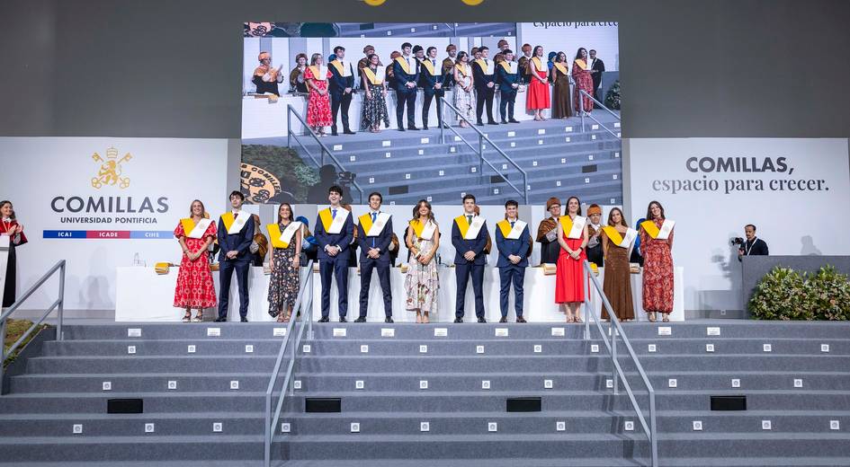 Graduación de estudiantes en la Universidad Pontificia Comillas, con un grupo posando en el escenario.