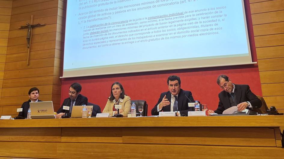 Una mesa de debate con cinco ponentes discutiendo temas relacionados con una presentación en un entorno académico.