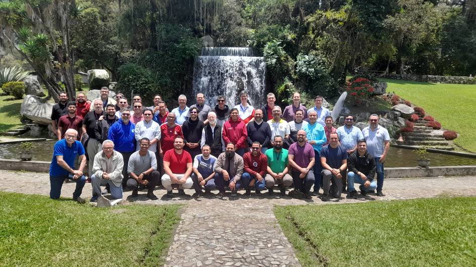 A group of men posing for a photo in front of a garden waterfall.