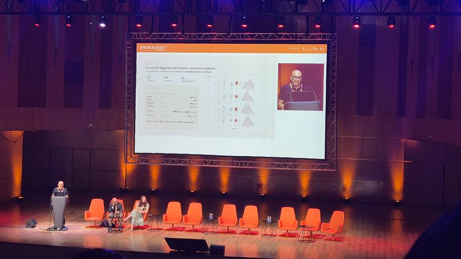 Una presentación en un escenario con un ponente y una pantalla mostrando información.