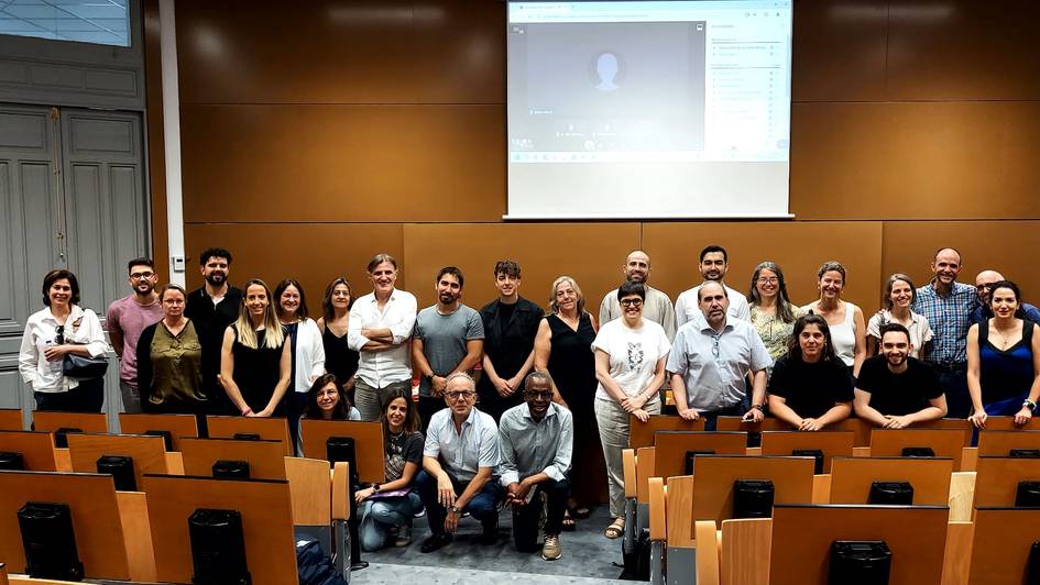 A group of people posing for a photo in an auditorium with a presentation screen in the background.