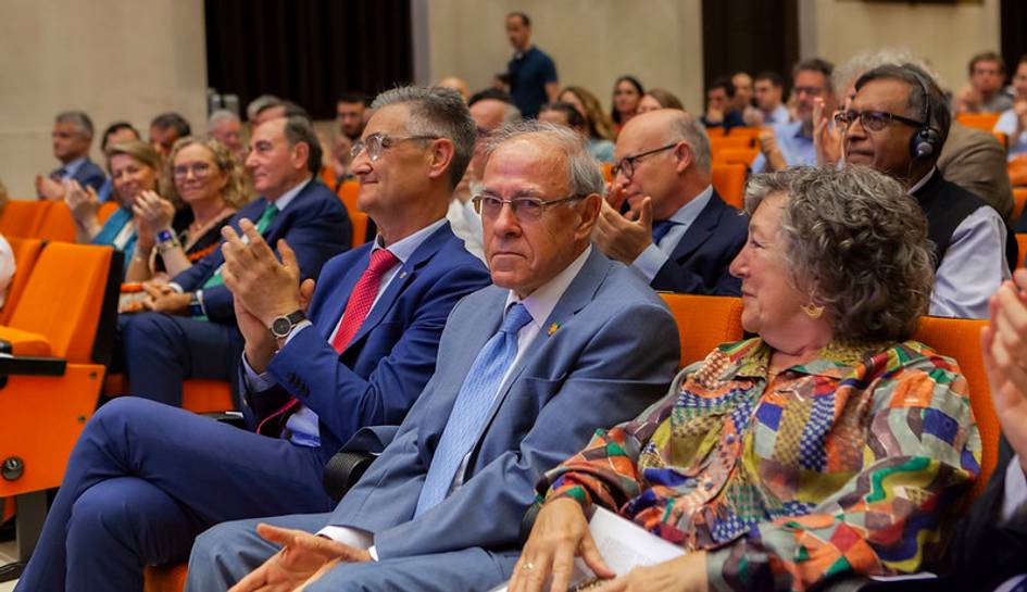 Audience members clapping at an event in an auditorium.