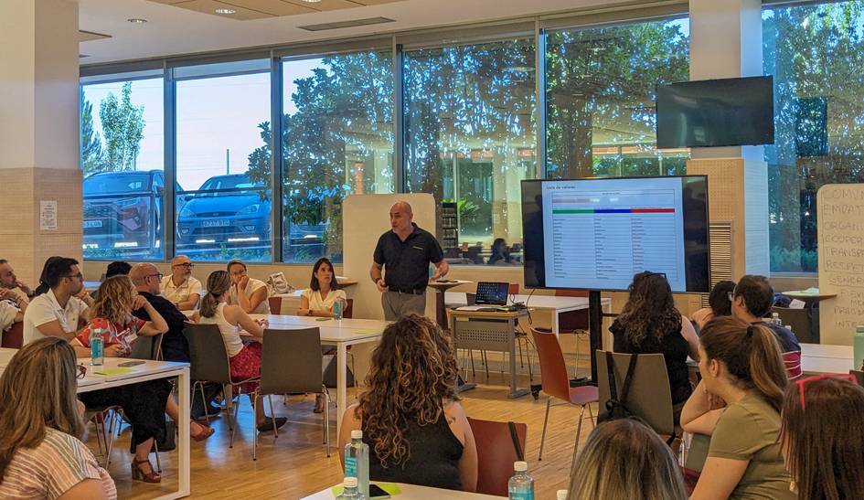 A man presenting to a group of attentive people in a modern classroom setting.